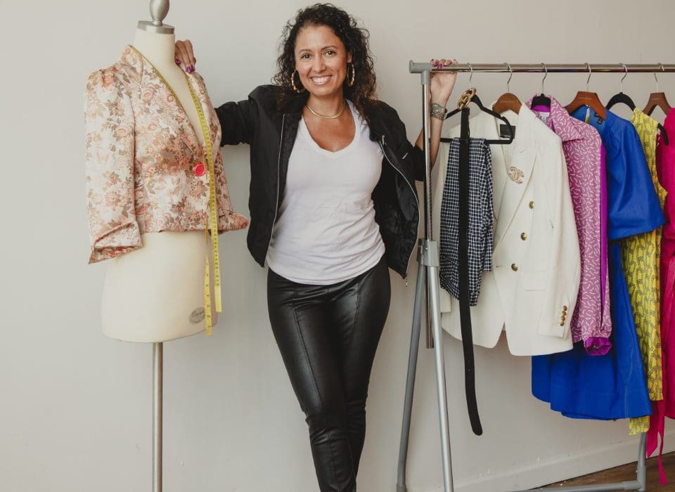 A woman standing next to some clothes on a rack