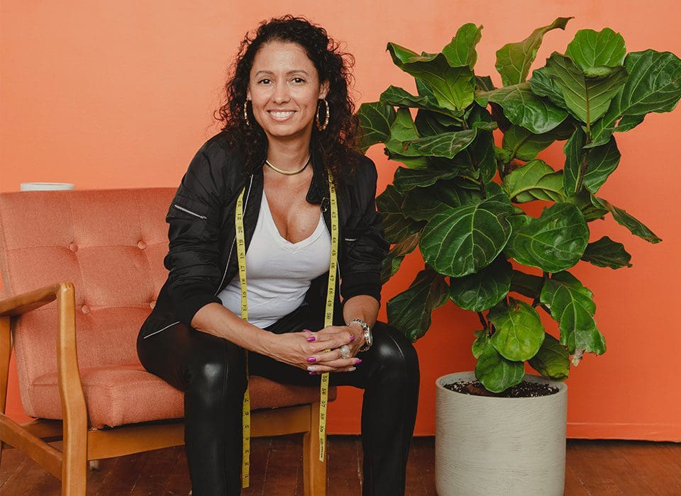 A woman sitting on the ground next to a plant.