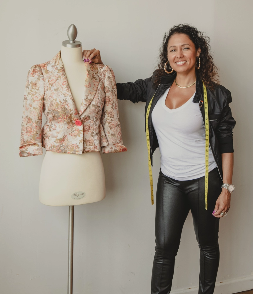A woman standing next to a mannequin with a jacket on.